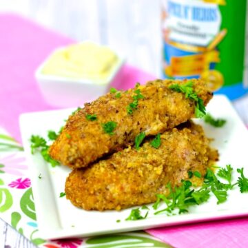 air fryer chicken tenders placed on a white plate on top of a pink and green napkin