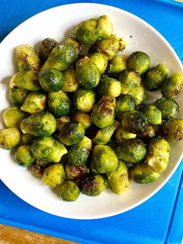 air fried frozen brussel sprouts served in a white bowl over a blue placemat